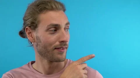 Here! Young fun guy 20s 30s years old in pink t-shirt isolated on blue Stock Footage 137457865