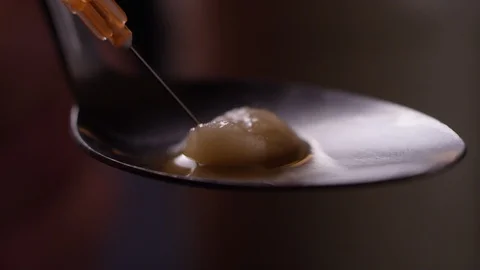 Heroin getting sucked up into a needle through a cotton ball in a spoon Stock Footage 119099951