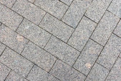 Herringbone granite pavers create a textured urban pavement pattern 库存照片
