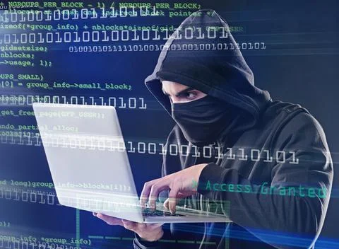 Hes about to crack the code. Shot of a computer hacker using a laptop while s Stockfoto's