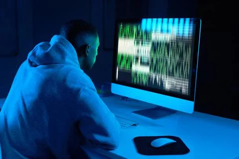 Hes always sticking to the code. Shot of a young male hacker cracking a compu 스톡 사진