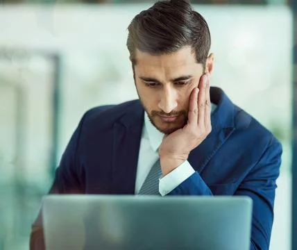 Hes a corporate problem solver. a focused executive working on a laptop in an Stock Photos