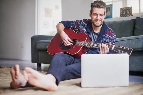 Hes found an easy tutorial to follow online. a handsome young man playing a Foto stock