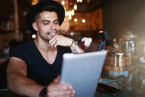 Hes got the menu in digital format. a young man using a digital tablet while Stock Photos