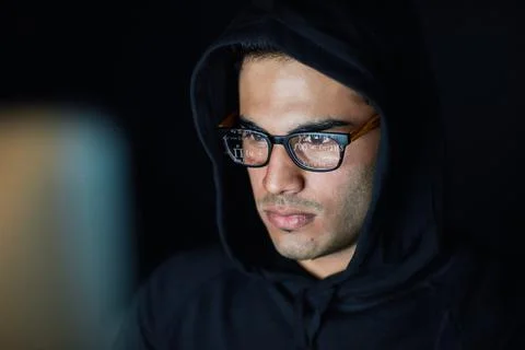 Hes got razor-sharp focus. a young hacker cracking a computer code in the dark. 写真素材