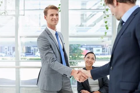 Hes just been promoted. two businessmen shaking hands in an office setting. Stock Photos