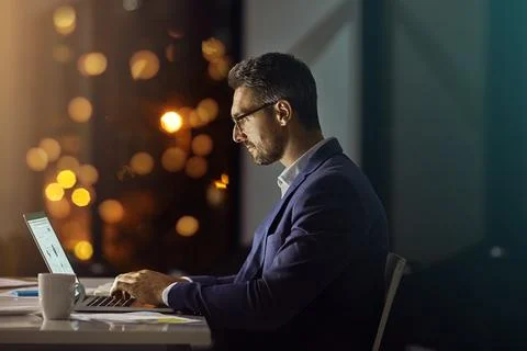 Hes keeping the commitment he made to his career. a businessman using a laptop Stock Photos