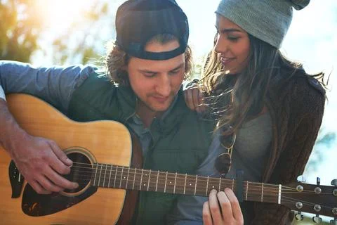 Hes stringing the right chord in my heart. a young man playing his girlfriend a Stock Photos