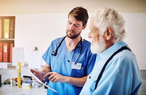 Hes using his tablet to explain the treatment methods available. a young doctor Stock Photos