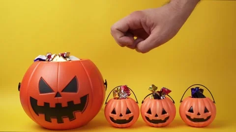 Hesitant hand picking candy from halloween pumpkin head Stock Footage 209332864
