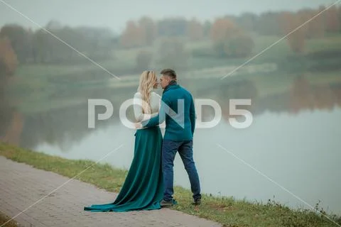 A heterosexual couple in love hugs and walk near the city's natural lake Stock Photos