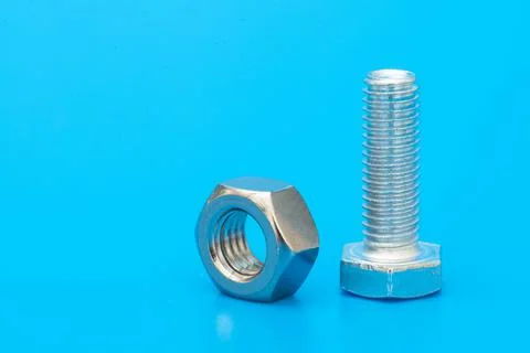 Hex bolt and nut on a blue background. Copy space for text. Stock Photos