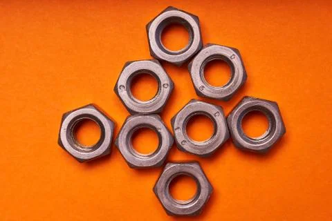 Hex nuts on orange background. Bolted connection elements Stock Photos