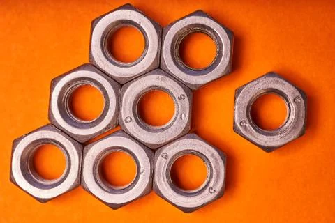 Hex nuts on orange background. Bolted connection elements Stock Photos