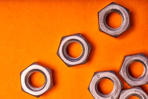 Hex nuts on orange background. Bolted connection elements Stock Photos