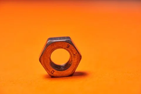 Hex nuts on orange background. Bolted connection elements Stock Photos