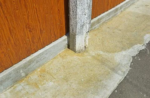 The hexagonal concrete column is concreted in the sidewalk near a metal fence Stock Photos