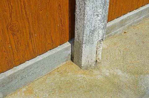 The hexagonal concrete column is concreted in the sidewalk near a metal fence Stock Photos