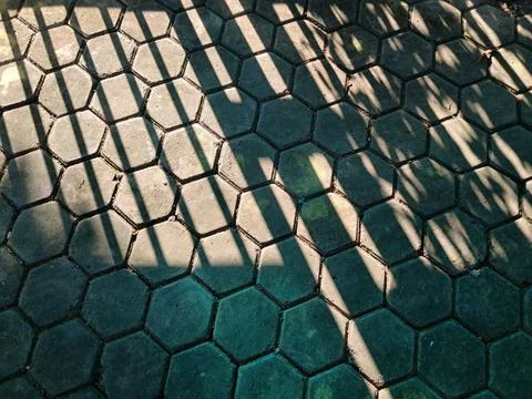 Hexagonal concrete paving block texture with dramatic fence shadows. Stock Photos