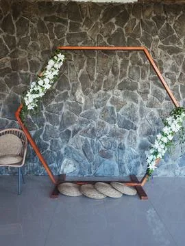 Hexagonal frame stands against stone wall Фото