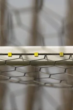 Hexagonal galvanized wire mesh secured with yellow plastic clips on metal frame Stock Photos