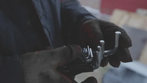 Hexagonal hand wrenches in mechanic hands wearing in dirty protective gloves Video stock 260552489