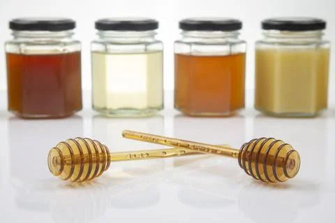 Hexagonal jars with different types and colors of fresh flower honey and a ho Stock Photos
