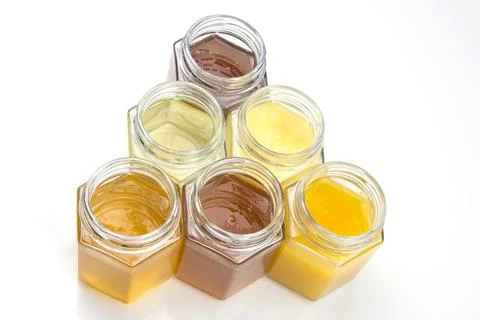 Hexagonal jars with different types and colors of fresh flower honey. vitamin Stock Photos