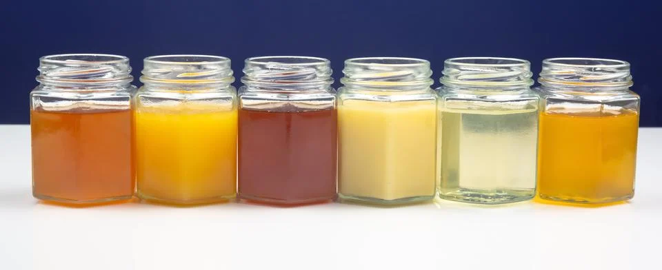 Hexagonal jars with different types and colors of fresh flower honey. vitamin Stock Photos