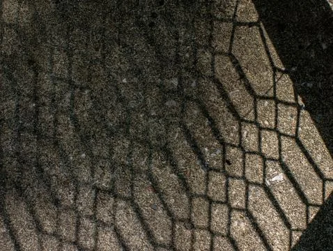 Hexagonal Net Shadow Pattern Cast on Sand Textured Ground Surface Stock Photos