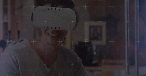 Hexagonal shapes and data processing against caucasian man wearing vr headset Foto stock