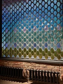 Hexagonal stained glass window above exposed brick wall and vintage radiato.. Stock Photos