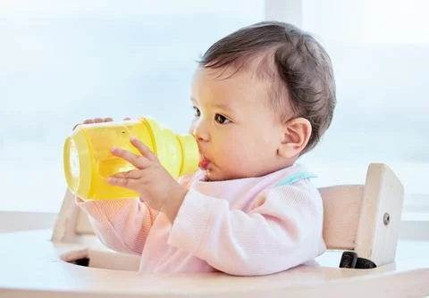 Hey, everyone likes a drink okay. a sweet baby girl drinking a bottle at home. Stock Photos