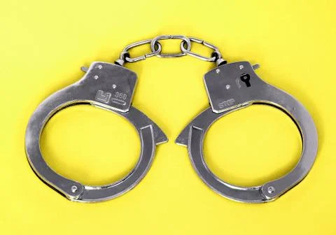 Hhandcuffs on yellow background Stock Photos