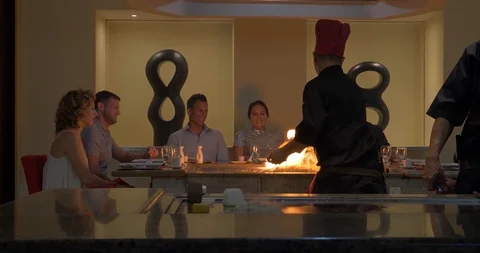Hibachi Chef Lighting Fire While Cooking, Friends at Asian Restaurant Stock Footage 103220584
