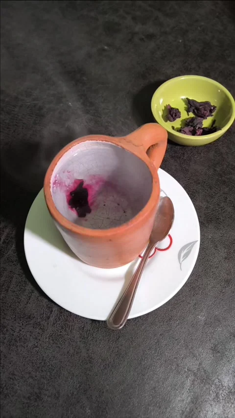 A hibiscus flower petal dissolving in a cup of hot water, viewed from above Stock Footage 345082262