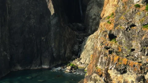 A Hidden Coastal Oasis Revealed: Dramatic Volcanic Cliffs Bathed in Golden Hour Vídeos de archivo 336219795