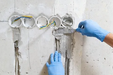 Hidden installation of electrical wires for sockets to a concrete wall. The Stock Photos