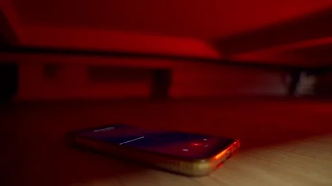 Hidden phone under bed or couch is secretly recording sound and audio on app Stock Footage 309471286