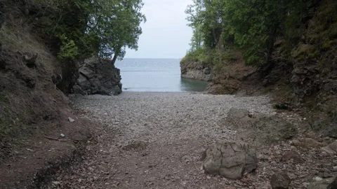 A hidden rocky beach surrounded by pines, 4k, slow-mo Stock Footage 243531689