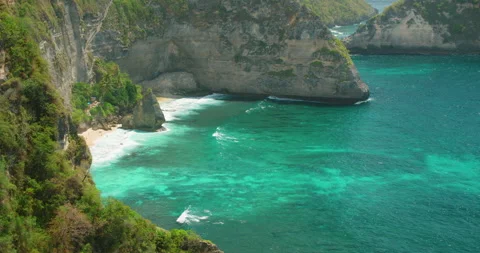 Hidden sandy cove beneath steep cliffs at Diamond Beach Nusa Penida coastline Stock-Footage 327497623