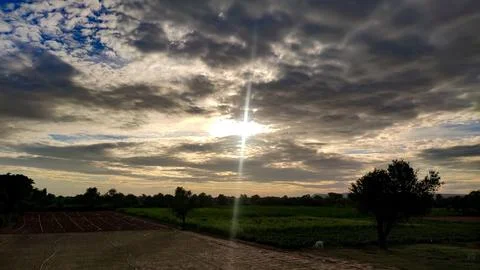 Hidden sun behind the clouds with agricultural landscape Stock Photos