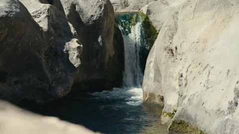 Hidden Waterfall Pouring Into a Dark Rock Pool Stock Footage 334509079