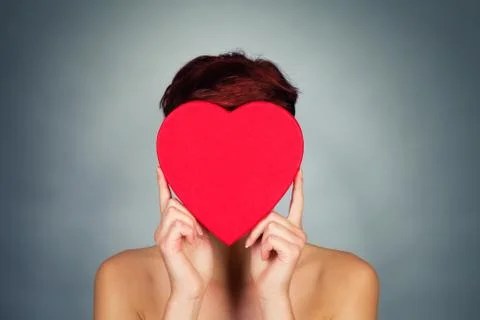 Hiding face behind red heart Stock Photos