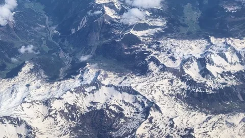 High above the Earth, at clouds level. Mountain relief seen from a flying plane. Stock Footage 303828585