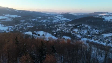 High above a mountain village blanketed in snow, drone records the sunset's.. Video stock 262310053