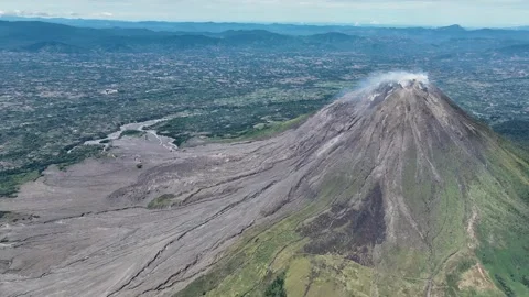 From high above, Sinabung dominates the landscape, a solitary giant rising from Stock Footage 328208722