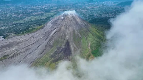 From high above, Sinabung dominates the landscape, a solitary giant rising from Stock Footage 328210814