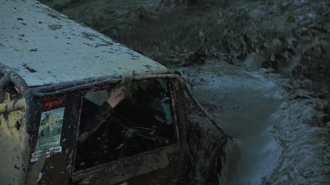 High-action, angled view of a muddy off-road vehicle creating a massive splash Stock Footage 345495944
