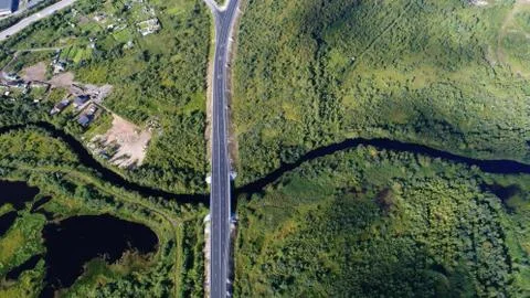 High aerial drone view of a bridge running through the dense forest Stock Photos